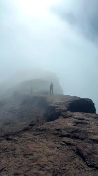 A trekker walking on the ridge with clouds moving in cinematic style at Harishchandragad, Maharashtra