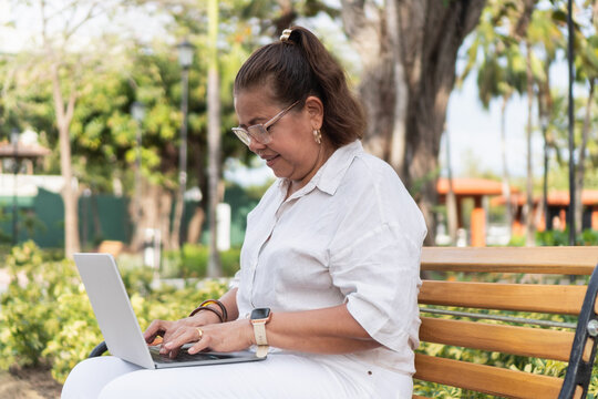 Woman working remotely on laptop at park bench