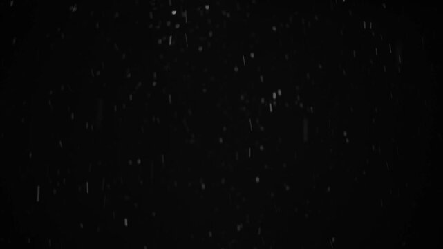 Snowflakes fall gently against a black background to form a winter atmosphere. The dark setting highlights the white snow, creating a simple yet dynamic effect
