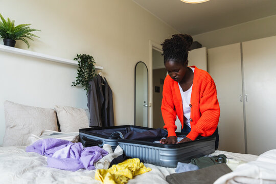 Young Woman Packing Suitcase for Travel in Bright Bedroom
