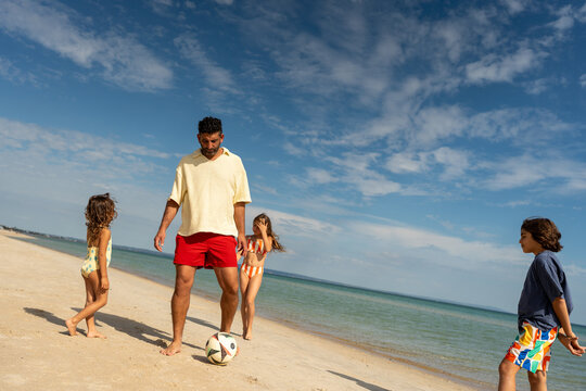 Family playing football together on the beach
