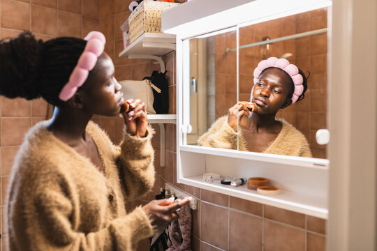 Woman Applying Face Makeup in Bathroom Mirror