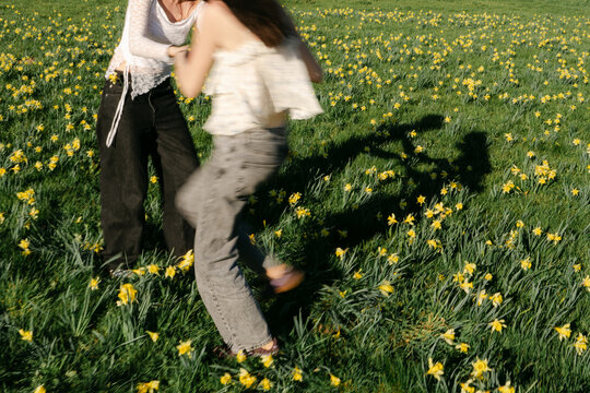 two young women twirling n a field of wild daffodils 