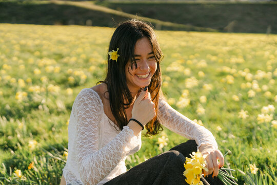 young woman in field of wild daffodil in teh evening sun 