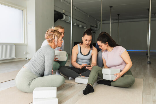 Women taking a break to check smartphone in yoga class