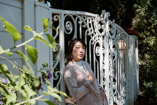 Non-binary model leaning against white iron gate