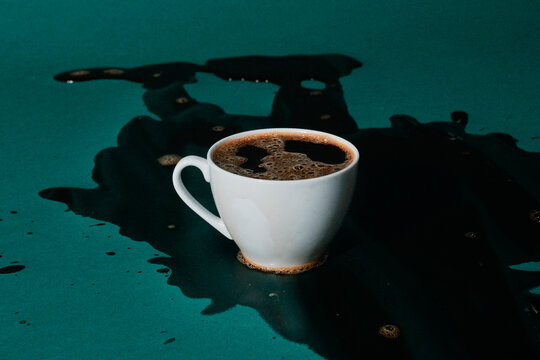 a single cup of coffee rests within a large dark spill