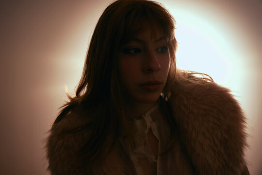 Moody backlit portrait of woman in faux fur coat