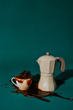 coffee overflows from a cup beside a moka pot