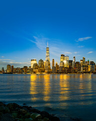 Fototapeta premium New York downtown skyline view. New York Manhattan skyscrapers illuminated. New York Hudson River reflection. New York night architecture.