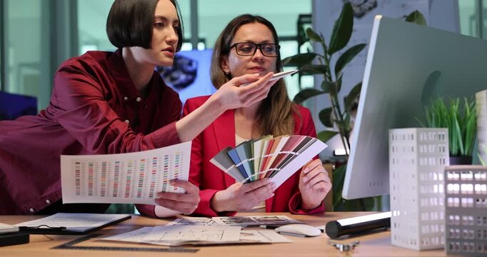 Architectural specialists examine creative paint combinations. Interior specialists discuss technical design details on computer. Slow motion