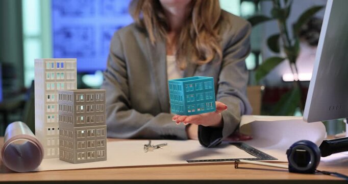 Architectural designer shows toy model of multi-story building. Woman discusses architectural concepts during business meeting. Slow motion