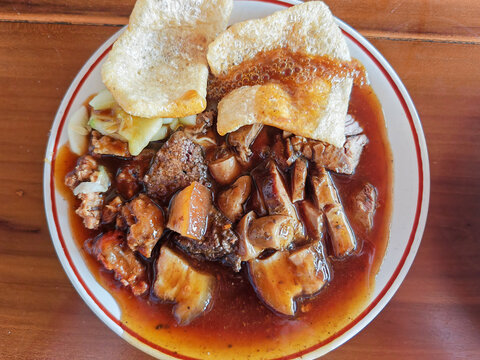 Balinese pork babi guling chunks served with thick savory gravy and crispy skin crackers
