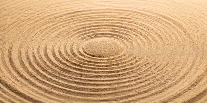 Zen garden sand pattern with concentric circular ripples and a centered mound for calm background