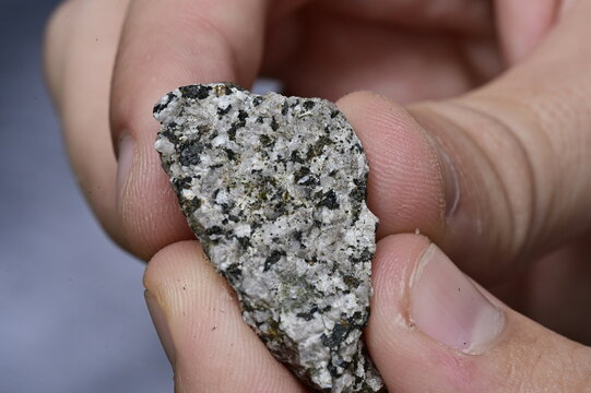 Close-Up of a Coarse-Grained Granite Rock Specimen Showing Intricate Mineral Crystals Held in Hand