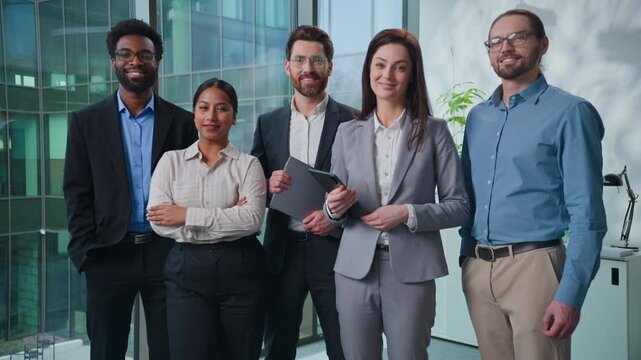 Portrait multiethnic Caucasian African Indian Arabian business team five men women businesspeople coworkers smile posing confident at workplace. Diversity office colleagues standing smiling happy