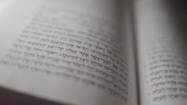 Jewish Hebrew open Bible book of Torah. Focus shifts gently from edges to center. Stillness suggests quiet reading or study. Ideal for educational, cultural