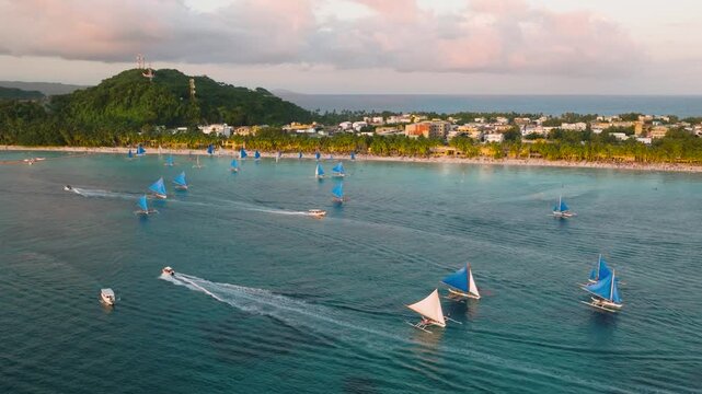 Tourist boats over turquoise water. White sandy beach with sunset reflection. Boracay, Philippines.