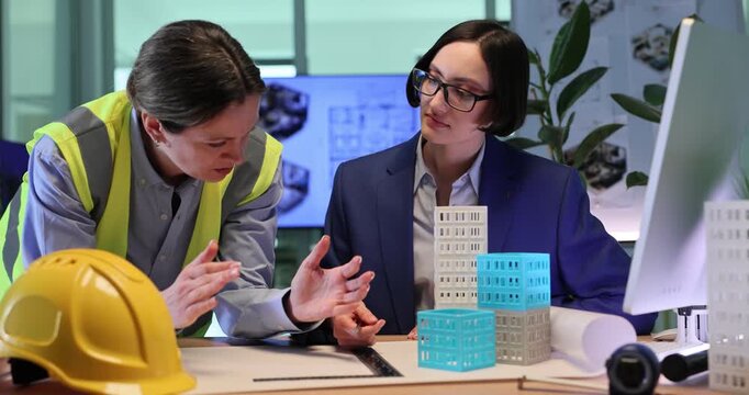Builder explains foundation work to architect during conversation about building project. Employees discuss future building stage. Slow motion