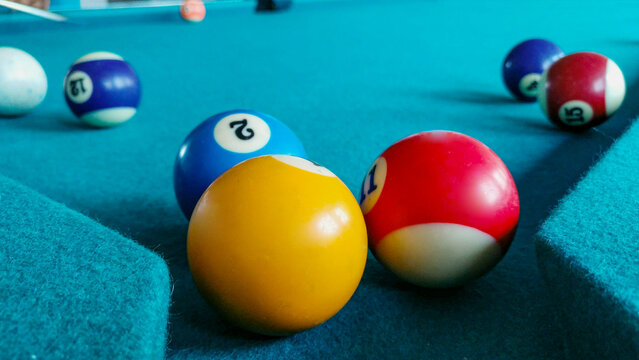 Close-up macro photograph of colorful billiard pool balls with authentic chalk marks on teal felt table