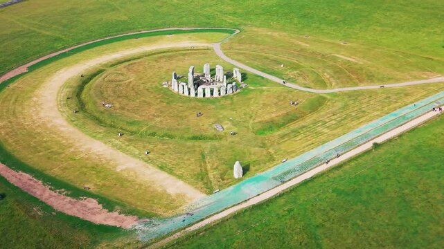 Aerial footage of Stonehenge in Wiltshire, England, showing the ancient stone circle, surrounding grassland, visitor paths and open Salisbury Plain landscape.