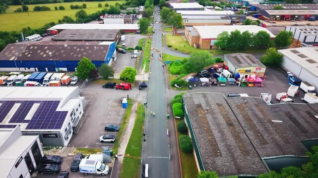 Editorial aerial footage of an industrial estate in Andover, Hampshire, England, showing warehouses, commercial buildings, a closed road soapbox derby course, barriers, spectators and surrounding