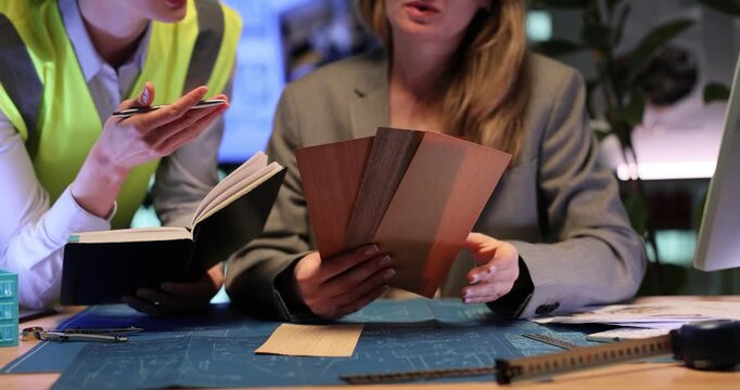 Women architects choose flooring materials for future luxury apartments. Builder discusses practical flooring solutions with director. Slow motion