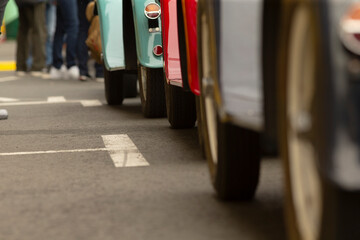 Fototapeta premium Low-angle view showing a line of colorful vintage cars parked curbside at an outdoor car show, emphasizing the lower halves, wheels, bumpers and painted