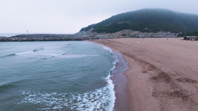 Drone aerial view of the Black Sea coastline near Agva Merkez, Turkey, on a foggy morning with sandy beach, calm waves and distant lighthouse.