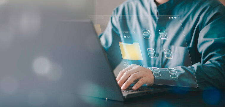 Businessman using laptop for digital data management. Virtual folder and document icons representing cloud storage, file organization and secure information system in a modern office.