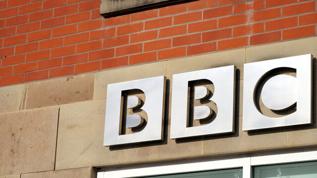 Leicester, England, UK - 30 May 2026: BBC corporate logo on building exterior, British Broadcasting Corporation metal signage on brick and stone wall, public broadcasting media headquarters