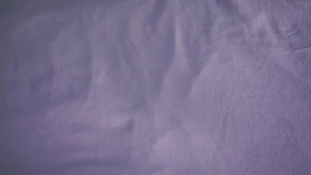 Person taking folded shirt from bed surface. Lifestyle footage highlighting wardrobe management, laundry routine, and household organization.