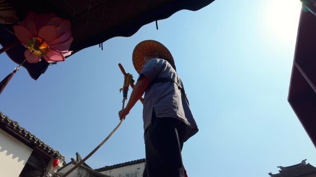 Man with straw hat poles boat under sunny sky, viewed from low angle outdoors