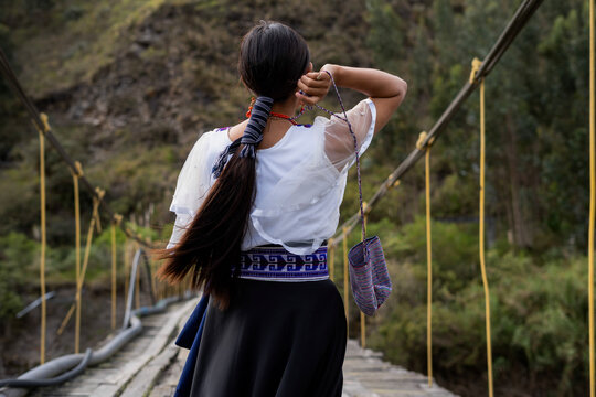 Indigenous kichwa woman walking on suspension bridge in ecuador