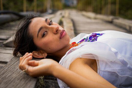 Young woman lying on wooden path looking at camera