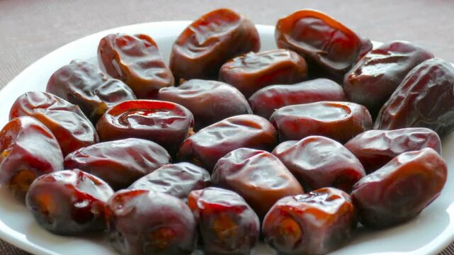 Close up of sweet dried dates rotating on a white plate