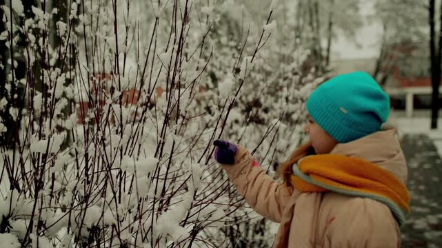 little beautiful girl in winter jacket in a snowy city park