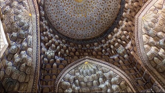 Panning shot of ornate golden muqarnas ceiling at Kusam Ibn Abbas mosque