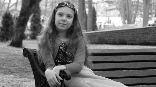 Little beautiful girl sitting on bench