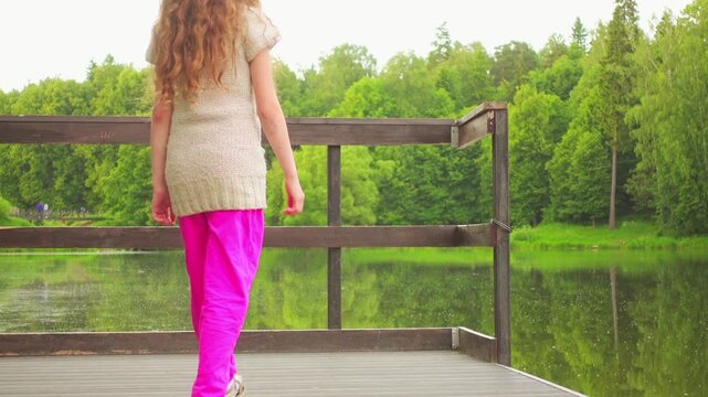 Beautiful little girl walking on a wooden bridge