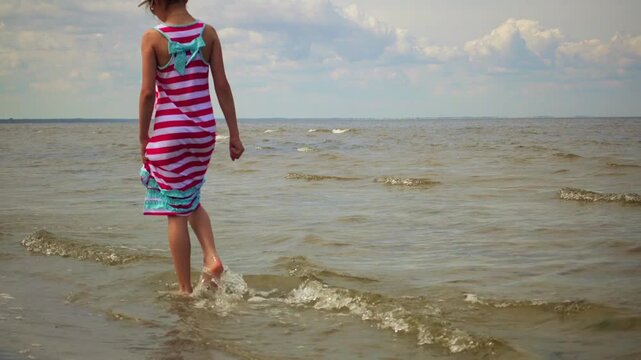 Little beautiful girl walks on beach in Jurmala