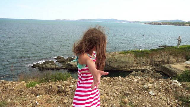 Little girl on rocky shore of sea