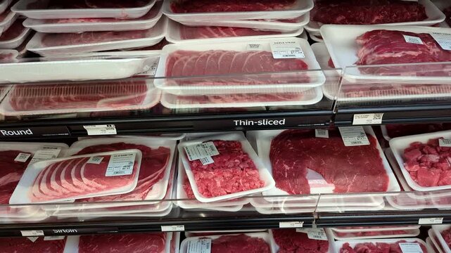 Aisle product showcase for meat in supermarket. Shopping in Supermarket. Many packaged raw red meat on supermarket shelves, assortment on showcase in butcher shop. Food, meats in supermarket, grocery.