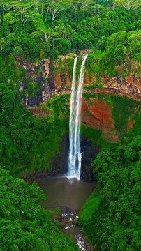 Aerial view of Chamarel Waterfall, plunging from verdant cliff into shadowy, the highest waterfall on the island, Mauritius island