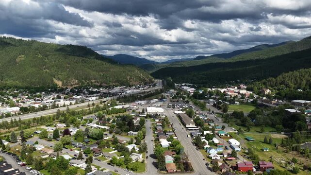 Wide Aerial of small town Kellogg Idaho near Coeur Dalene National Forest with overcast skies and dense forest coverage in spring
