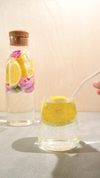 A woman puts a straw in a glass of lemon water