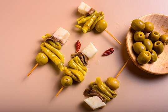 Traditional basque gilda tapas with green olives anchovies piparra peppers and cheese cubes with copy space on beige background