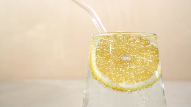 Close-up of a glass of clear water with lemon and a straw