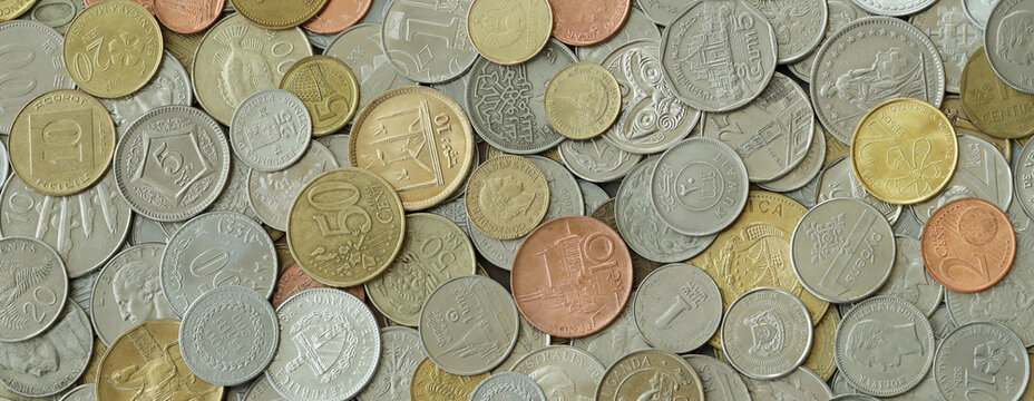 Pile of global currencies, various coin types visible up close. Different nations money together