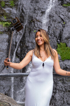 A Bolivian Latina woman on vacation taking a selfie at a waterfall in the town of Coroico in the Yungas region of Bolivia - the concept of a vacation